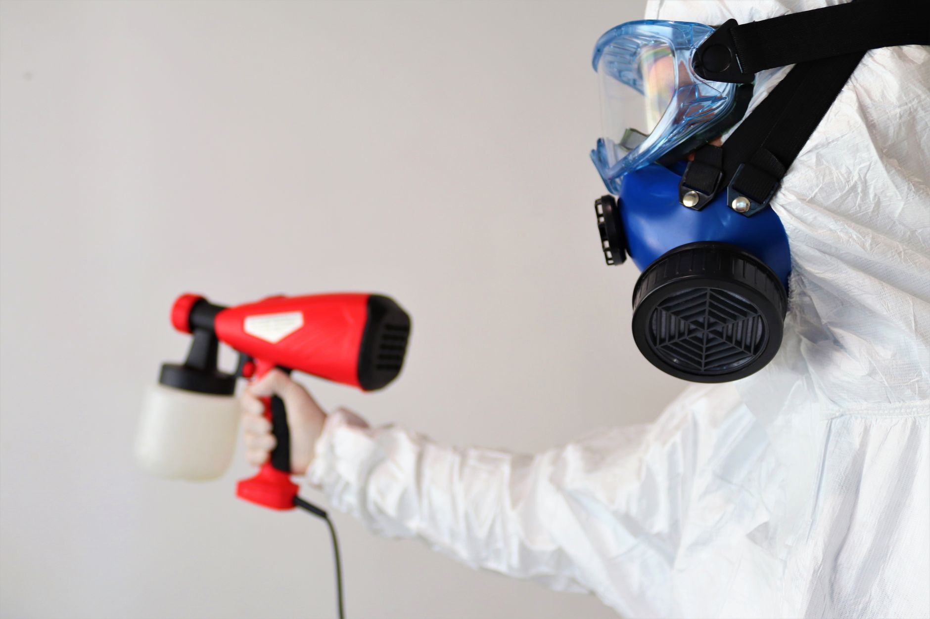 A certified mold remediation technician in May, Texas, wearing full PPE, carefully sealing off a contaminated area with plastic sheeting to prevent mold spore spread.
